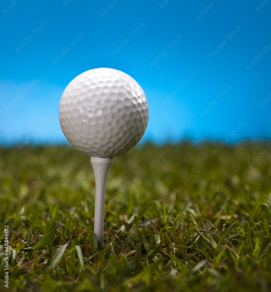 Golf ball on green grass over a blue background Golf ball on green grass over a blue background