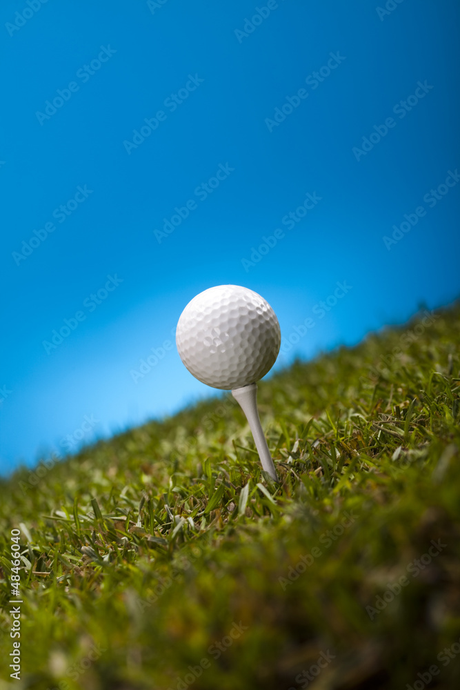 Golf ball on green grass over a blue background Golf ball on green grass over a blue background