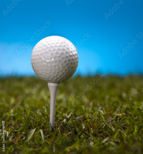  Golf ball on green grass over a blue background 