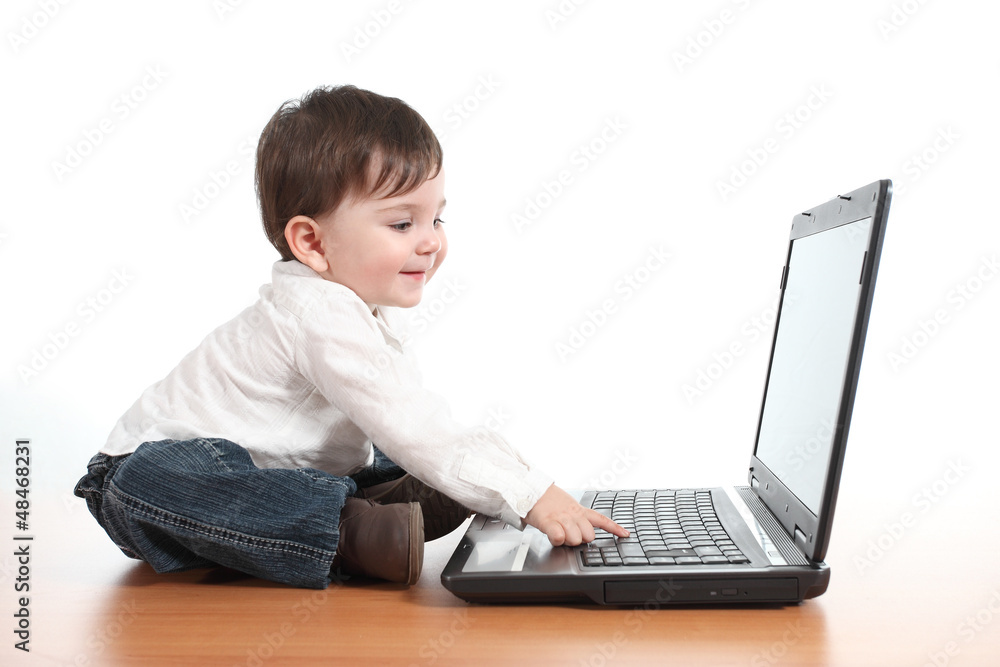 Casual baby smiling while is playing with a laptop computer Casual baby smiling while is playing with a laptop computer