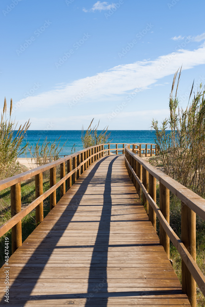 A footbridge leading to a Mediterranean resort beach