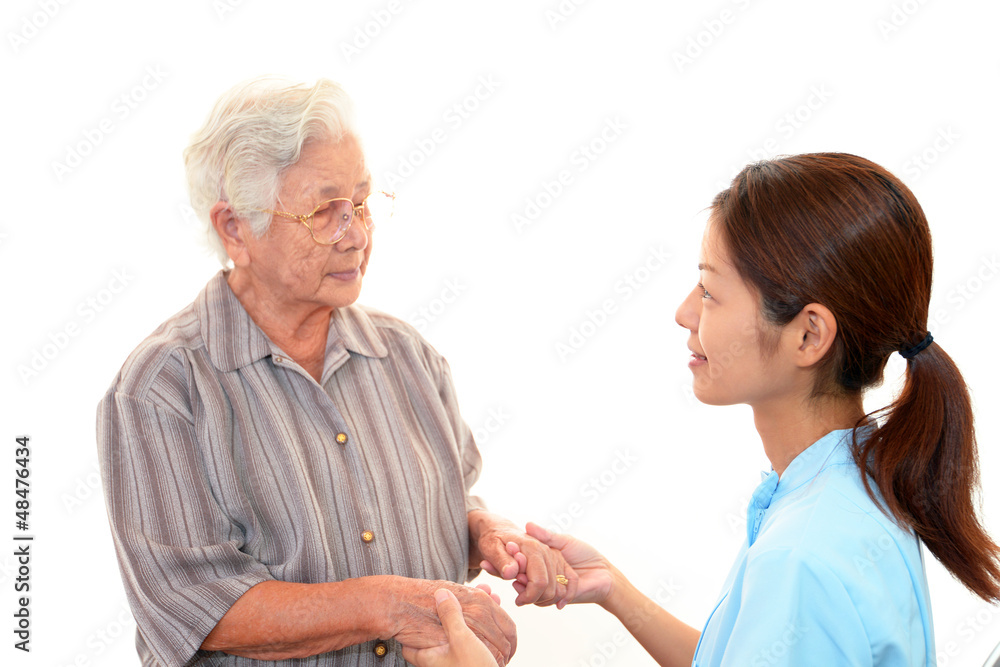 手を取り合い微笑む高齢者と介護士