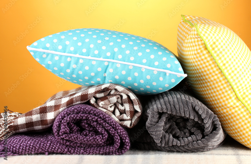 Fototapeta premium Plaids and color pillows on yellow background