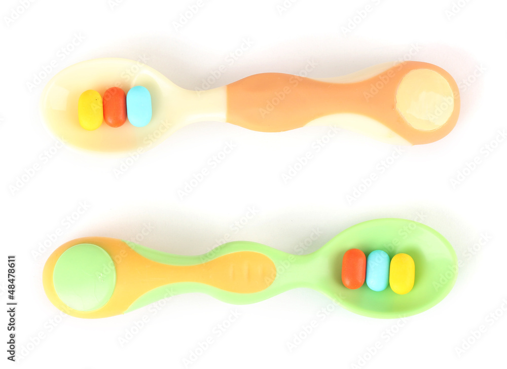 Plastic spoons with color pills, isolated on white Plastic spoons with color pills, isolated on white