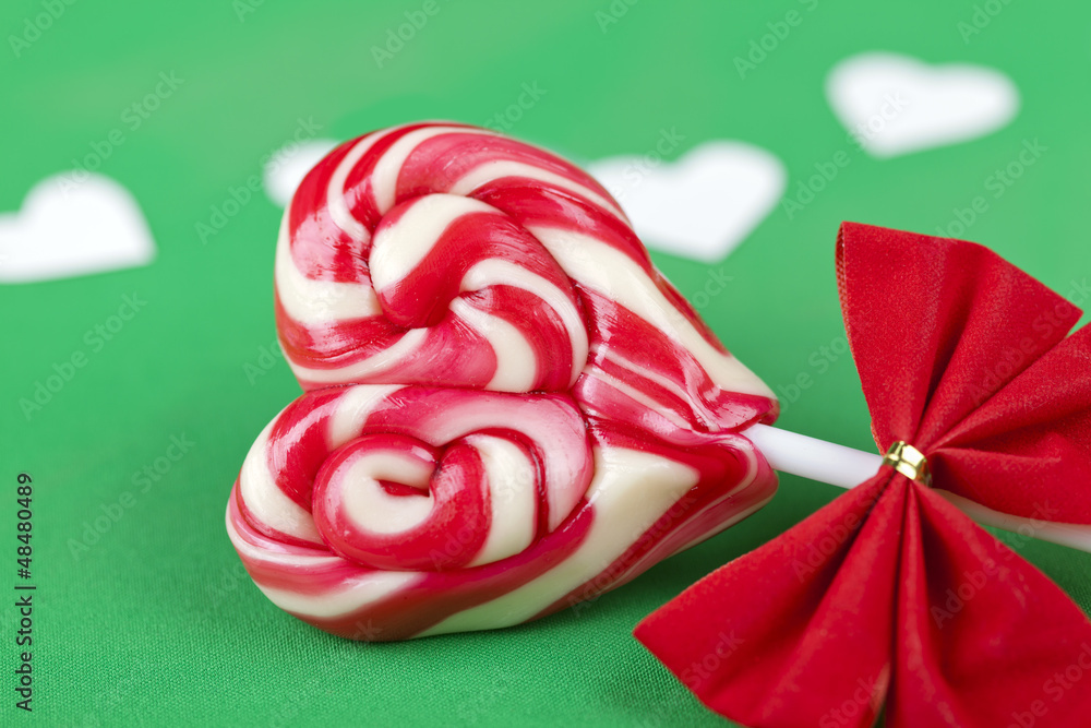 Close up of a heart shape candy next to papper heart shape cuts Close up of a heart shape candy next to papper heart shape cuts