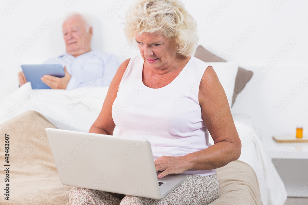 Aged couple using a tablet and the laptop Aged couple using a tablet and the laptop