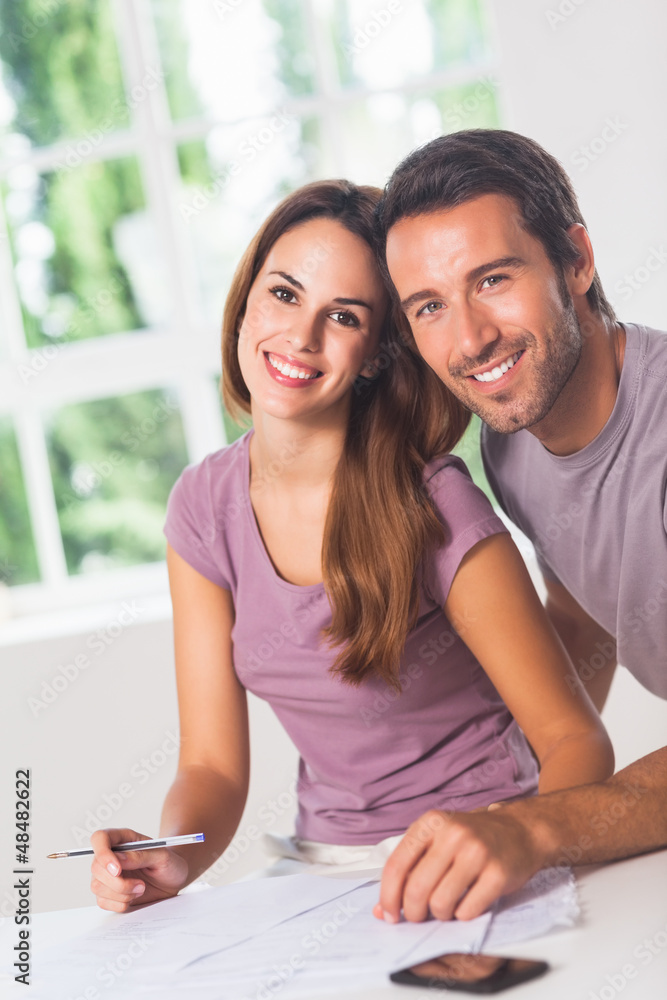 Couple smiling at the camera with invoices Couple smiling at the camera with invoices
