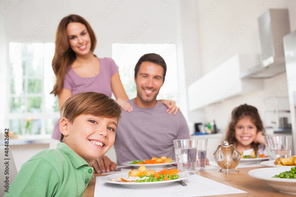 Family looking at the camera at dinner time Family looking at the camera at dinner time