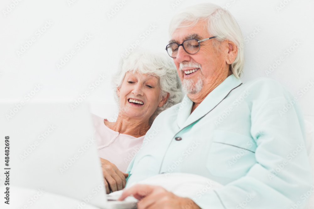 Couple watching something on laptop in bed Couple watching something on laptop in bed