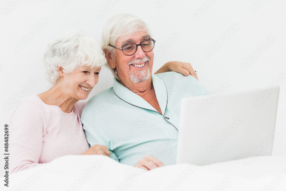 Couple using laptop in bed