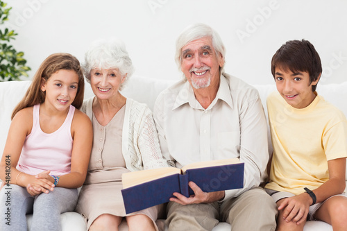 Smiling grandparents with grandchildren reading