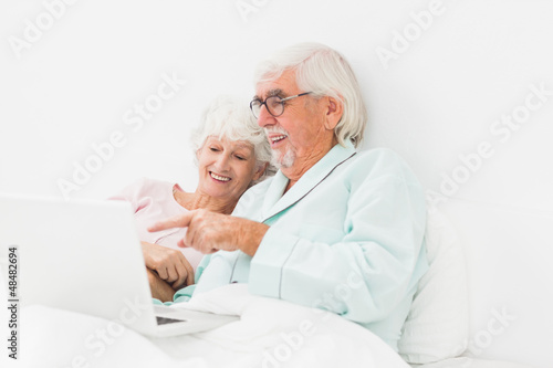 Happy couple using laptop in bed © WavebreakmediaMicro