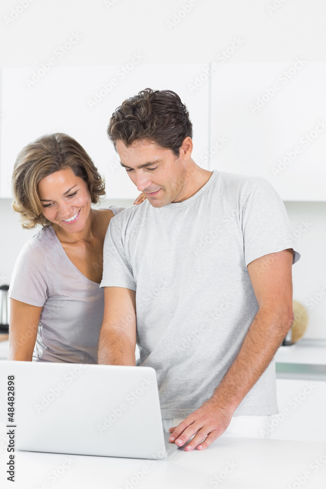 Smiling couple using laptop together Smiling couple using laptop together