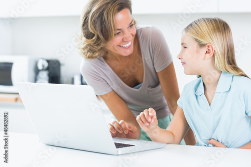 Smiling mother and daughter with laptop