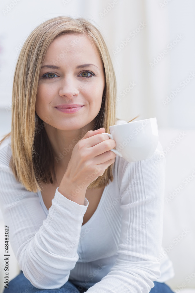 Portrait of woman with coffee cup sitting on couch Portrait of woman with coffee cup sitting on couch