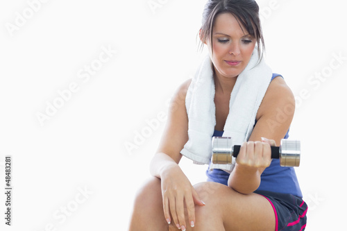 Young woman sitting and exercising with dumbbell