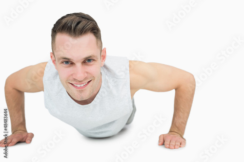 Portrait of smiling young man doing push ups