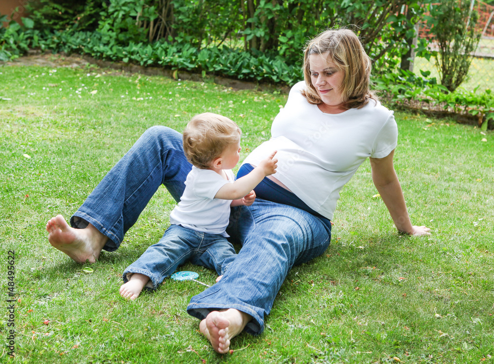 Young pregnant woman and little son in summer garden Young pregnant woman and little son in summer garden