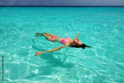 Woman in bikini lying on water