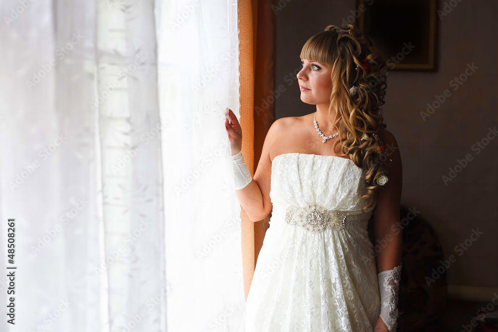 beautiful young bride is at a wedding in the room by window beautiful young bride is at a wedding in the room by window