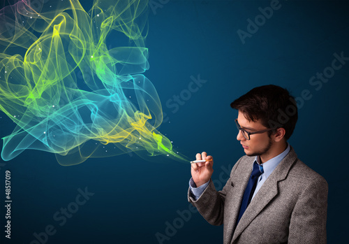 Handsome man smoking cigarette with colorful smoke