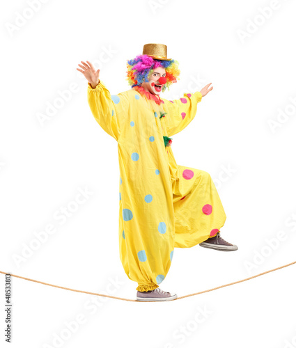 Full length portrait of a happy male clown walking on a rope photo