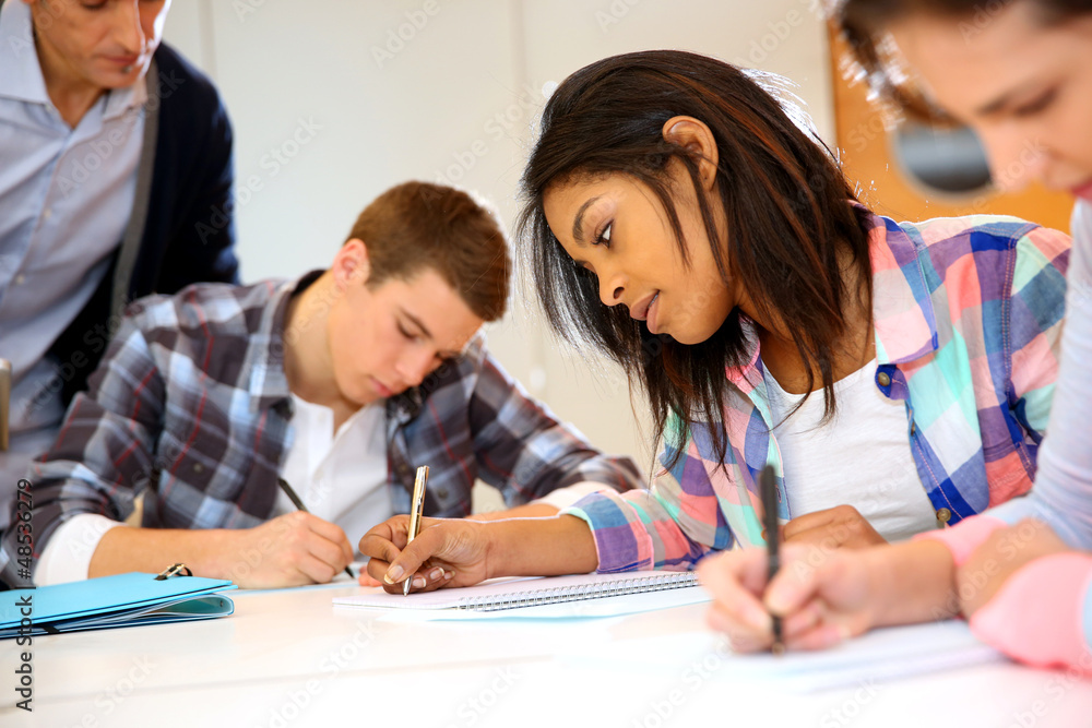 Group of teenagers in class writing an exam Group of teenagers in class writing an exam