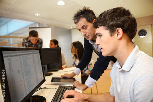 Adult man helping student in classroom photo