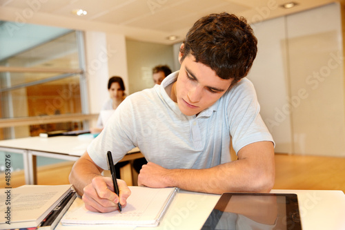 Portrait of student boy writing on notebook