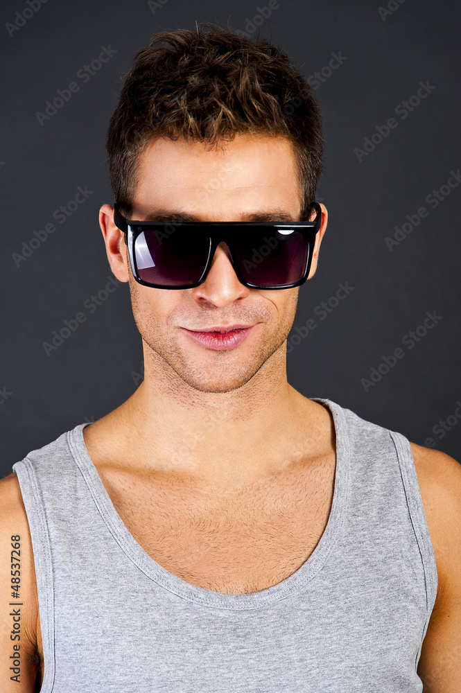 Handsome man in gray tanktop with smile and sunglasses Handsome man in gray tanktop with smile and sunglasses