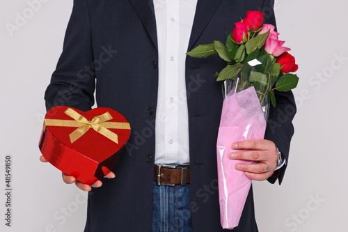 Man holding flowers and a box of chocolates
