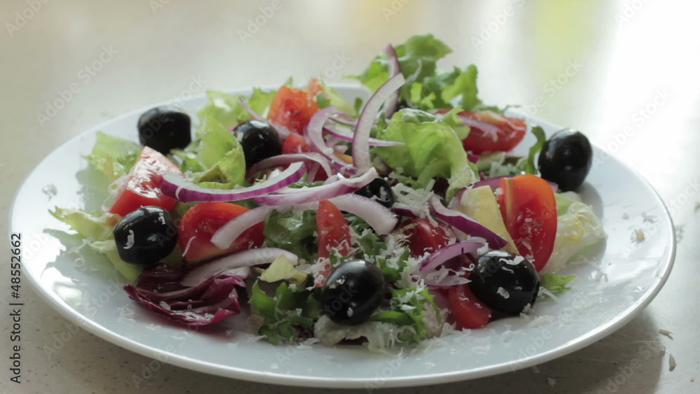 A chef grates fresh cheese onto a salad, close up A chef grates fresh cheese onto a salad, close up