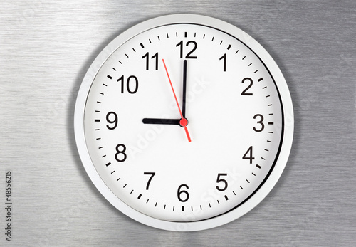 Classical clock on metal background displaying nine o'clock