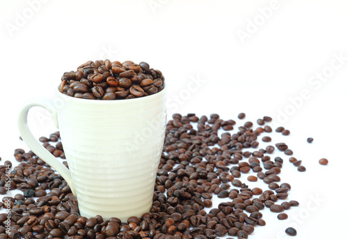 Cup full of coffee beans on white background