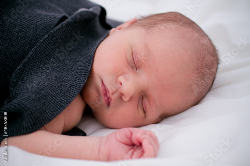 baby  sleeping on white sheets in bed
