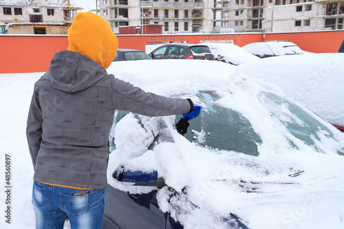 Woman scraping ice from the car window in winter time photo