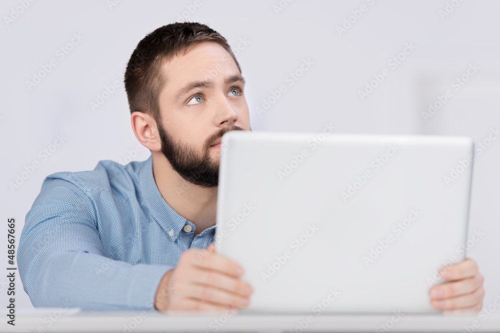 junger mann am laptop schaut nach oben junger mann am laptop schaut nach oben