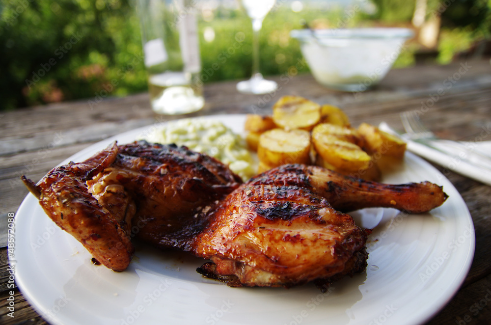 Grilled chicken with potatoes on rustical table outdoors