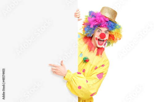 Funny circus clown posing behind a blank panel