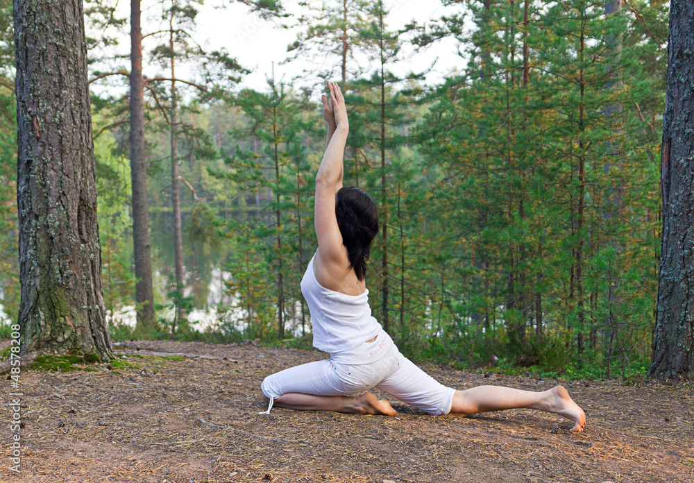Fototapeta premium Young woman Yoga one legged king pigeon pose in the forest