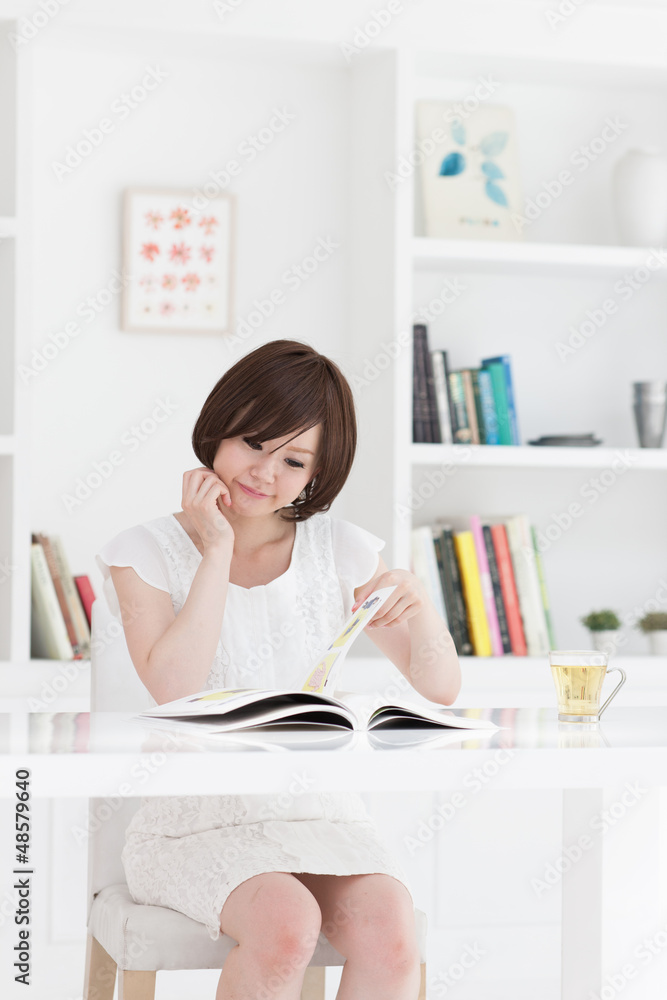 部屋で雑誌を読む若い女性