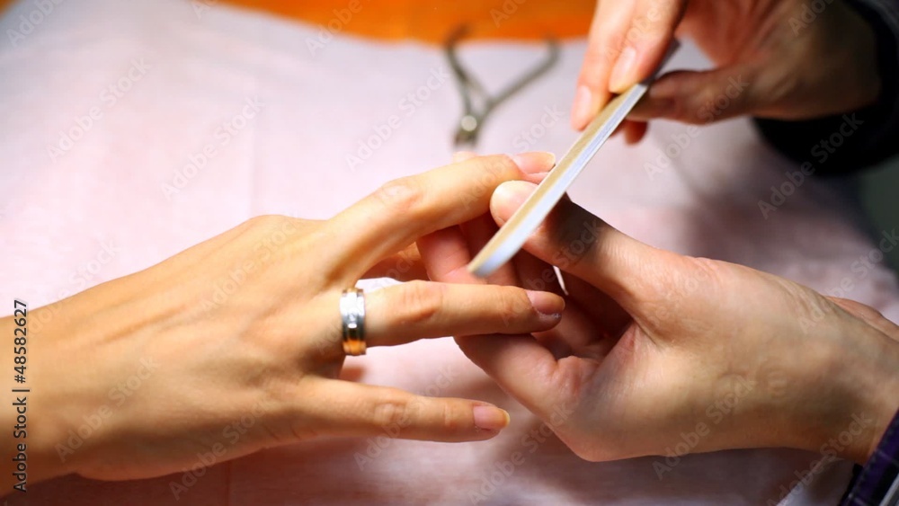 Cosmetician does manicure and saws nails of client file Cosmetician does manicure and saws nails of client file