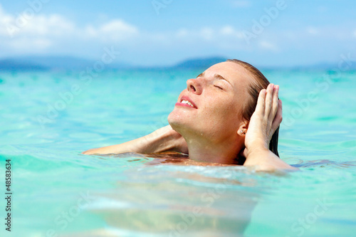 Beautiful young woman enjoying swimming in refreshing sea water