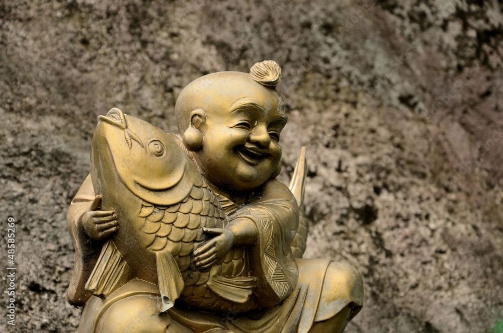 Golden, laughing Buddhist monk with fish of good fortune