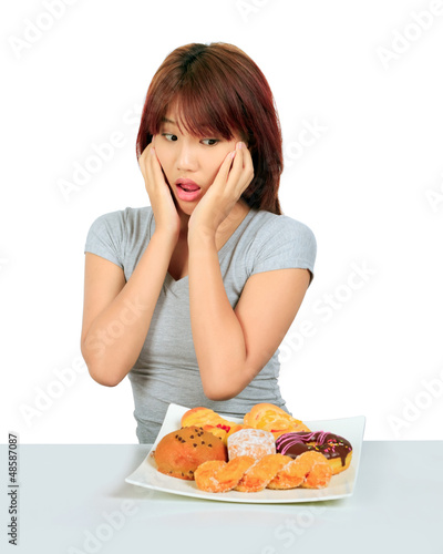 Isolated young asian woman with a donuts on the table