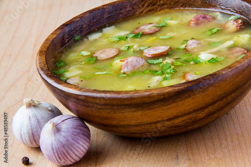 Pea soup with smoked sausages in a wooden plate