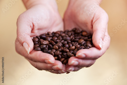 Coffee beans in woman palms