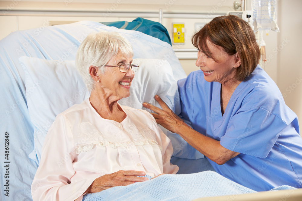 Fototapeta premium Nurse Talking To Senior Female Patient In Hospital Bed