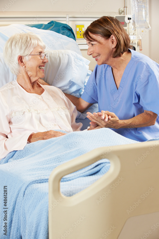 Obraz premium Nurse Talking To Senior Female Patient In Hospital Bed