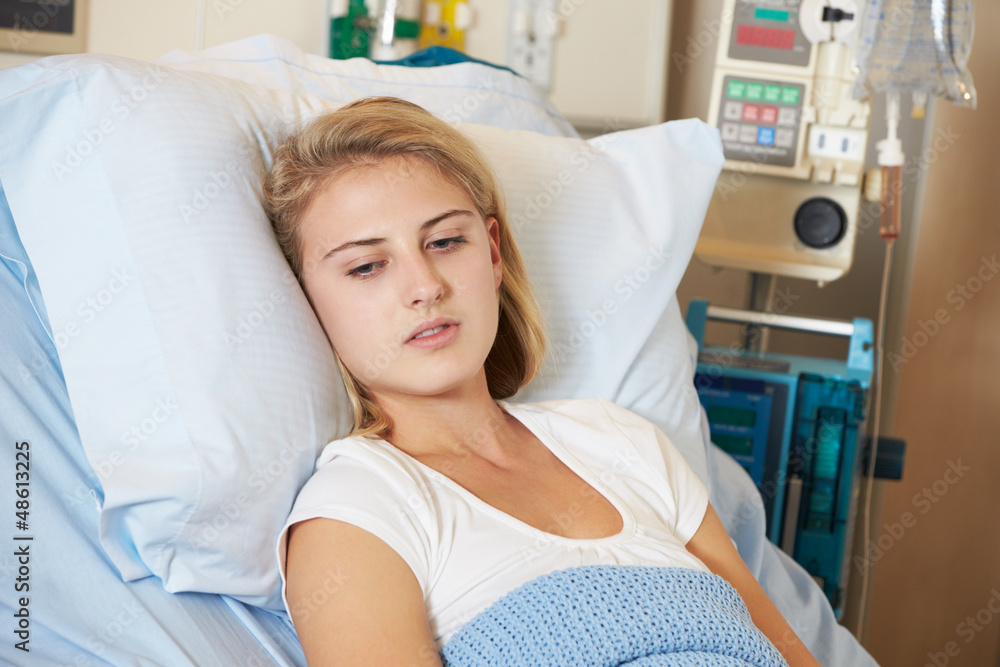 Depressed Teenage Female Patient Lying In Hospital Bed Stock Photo
